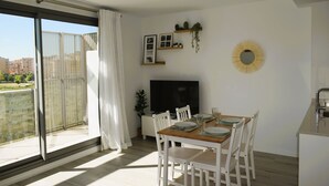 A modern dining area with a large window, a flat-screen TV, and a dining table set for four. - Ap2242 in Denia With 2 Bedrooms and 2 Bathrooms (Denia)