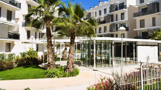 A modern hotel with white exterior walls, multiple balconies, and a glass-enclosed dining area. - Ap2242 in Denia With 2 Bedrooms and 2 Bathrooms (Denia)