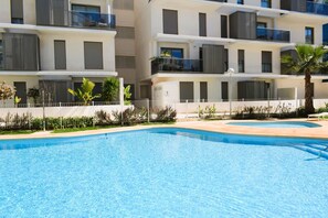 En moderne bygning med altaner, swimmingpool og en lukket have.