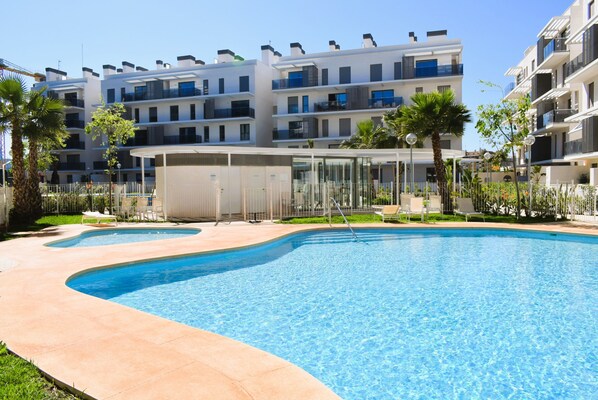 A modern apartment building with a swimming pool, palm trees, and outdoor seating areas. - Ap2242 in Denia With 2 Bedrooms and 2 Bathrooms (Denia)