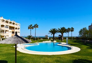 Ein Pool, umgeben von Palmen und einem Gebäude mit Balkonen.