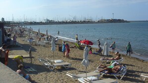 A beach with sun loungers, umbrellas, and people enjoying the seaside. - Ap2215 in Denia With 2 Bedrooms and 2 Bathrooms (Denia)
