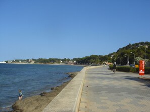 A coastal walkway with a concrete path, a cyclist, and a child near the water. - Ap2215 in Denia With 2 Bedrooms and 2 Bathrooms (Denia)