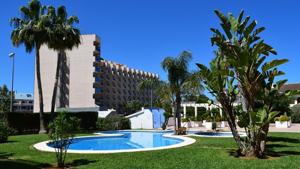 A hotel with a pool surrounded by palm trees and a well-maintained lawn. - Ap2215 in Denia With 2 Bedrooms and 2 Bathrooms (Denia)