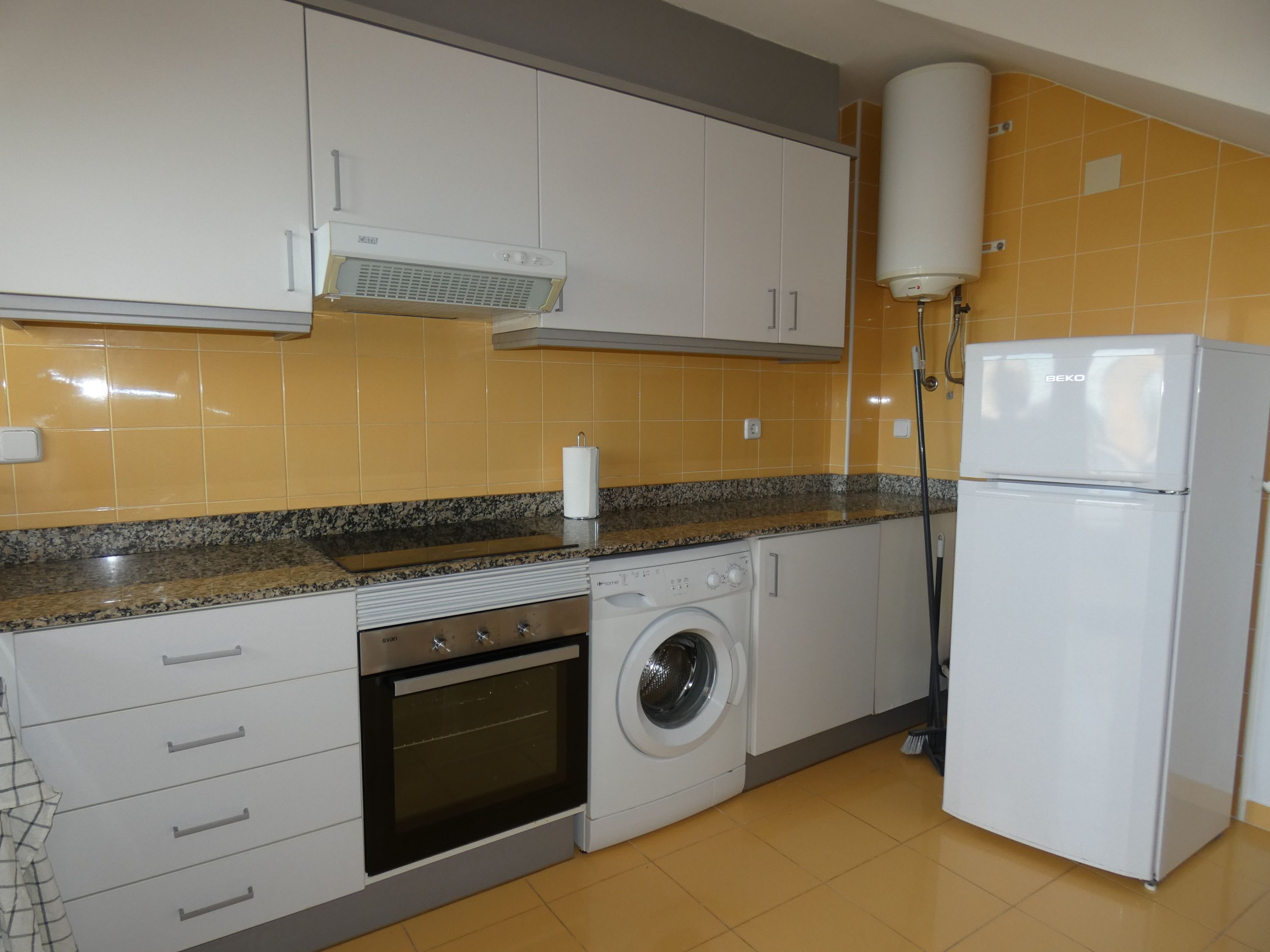 A kitchen with a washing machine, oven, and a refrigerator.
