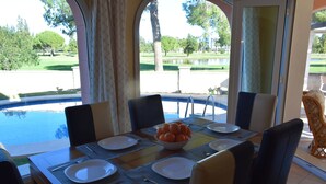 Une table à manger dressée pour quatre personnes, avec un saladier rempli d’oranges, des assiettes et des couverts.