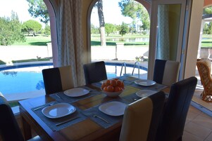 A dining table set for four with a bowl of oranges, plates, and cutlery.