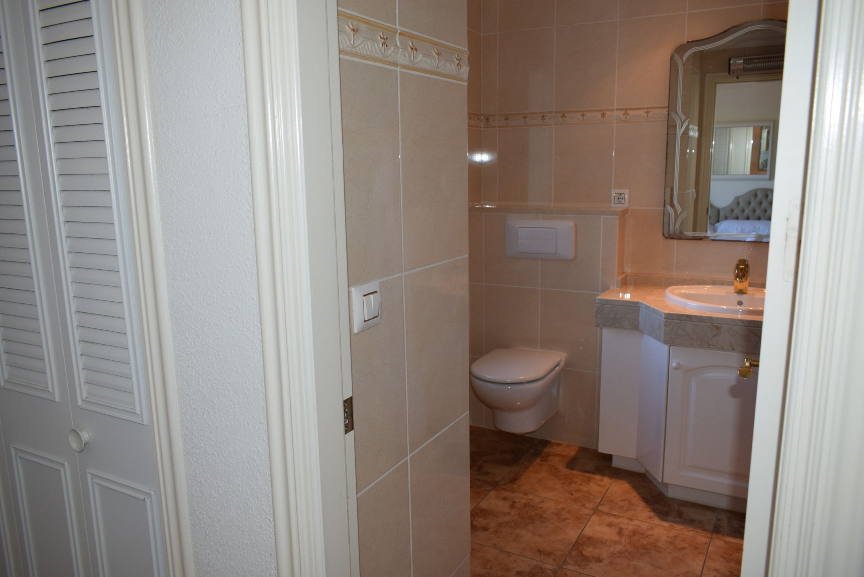 A bathroom with a toilet, sink, and mirror.