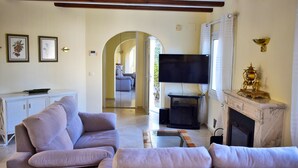 A living room with a sofa, TV, fireplace, and a view into another room. - Ch1015 in Oliva With 5 Bedrooms and 5 Bathrooms (Oliva)