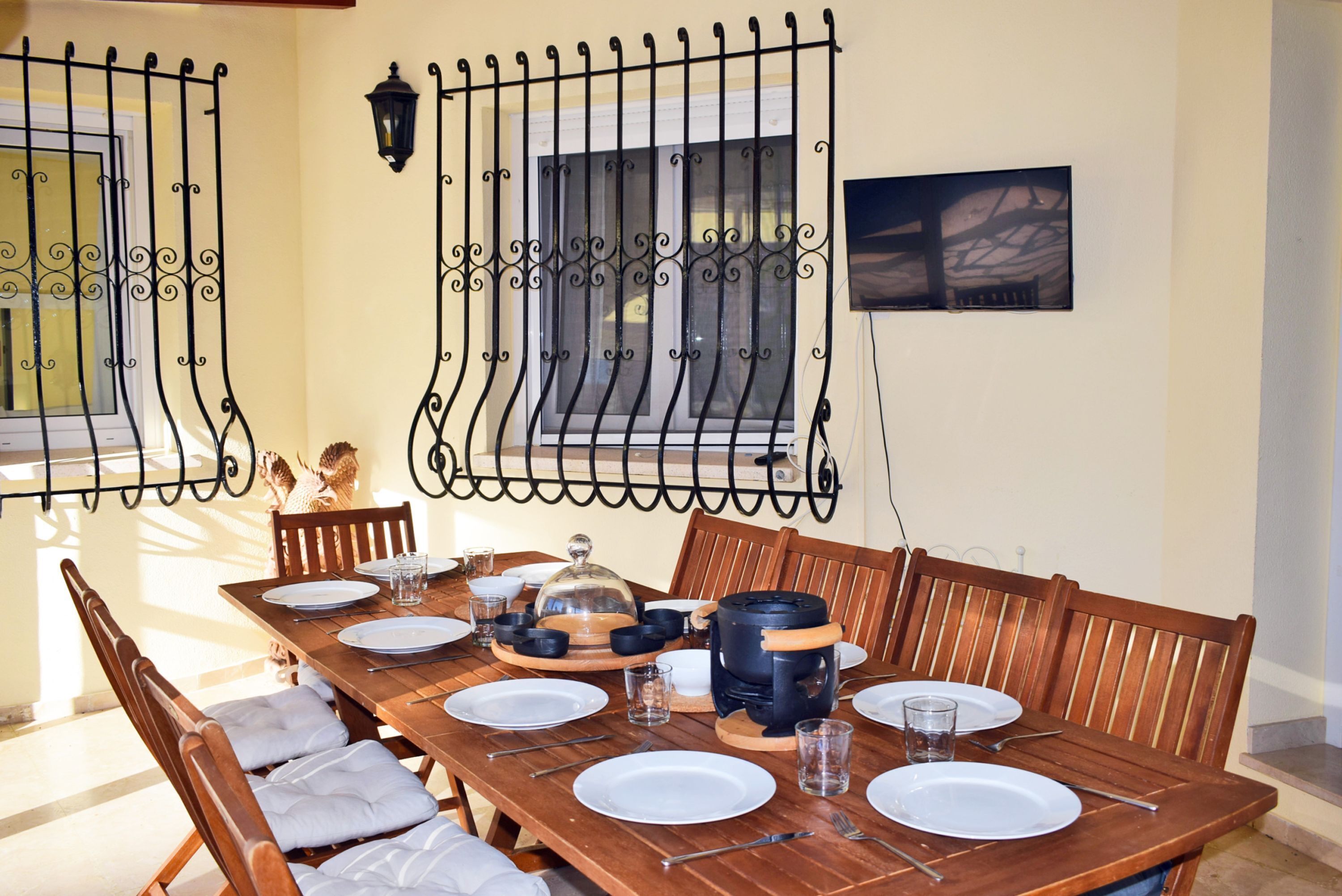 A dining area with a wooden table set for four, surrounded by chairs with cushioned seats.