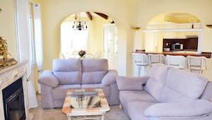 A living room with a fireplace, a sofa, a coffee table, and a kitchen area with a bunk bed. - Ch1015 in Oliva With 5 Bedrooms and 5 Bathrooms (Oliva)