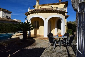 Eine Villa mit Pool, Sitzgelegenheiten im Freien und einem Ziegeldach.