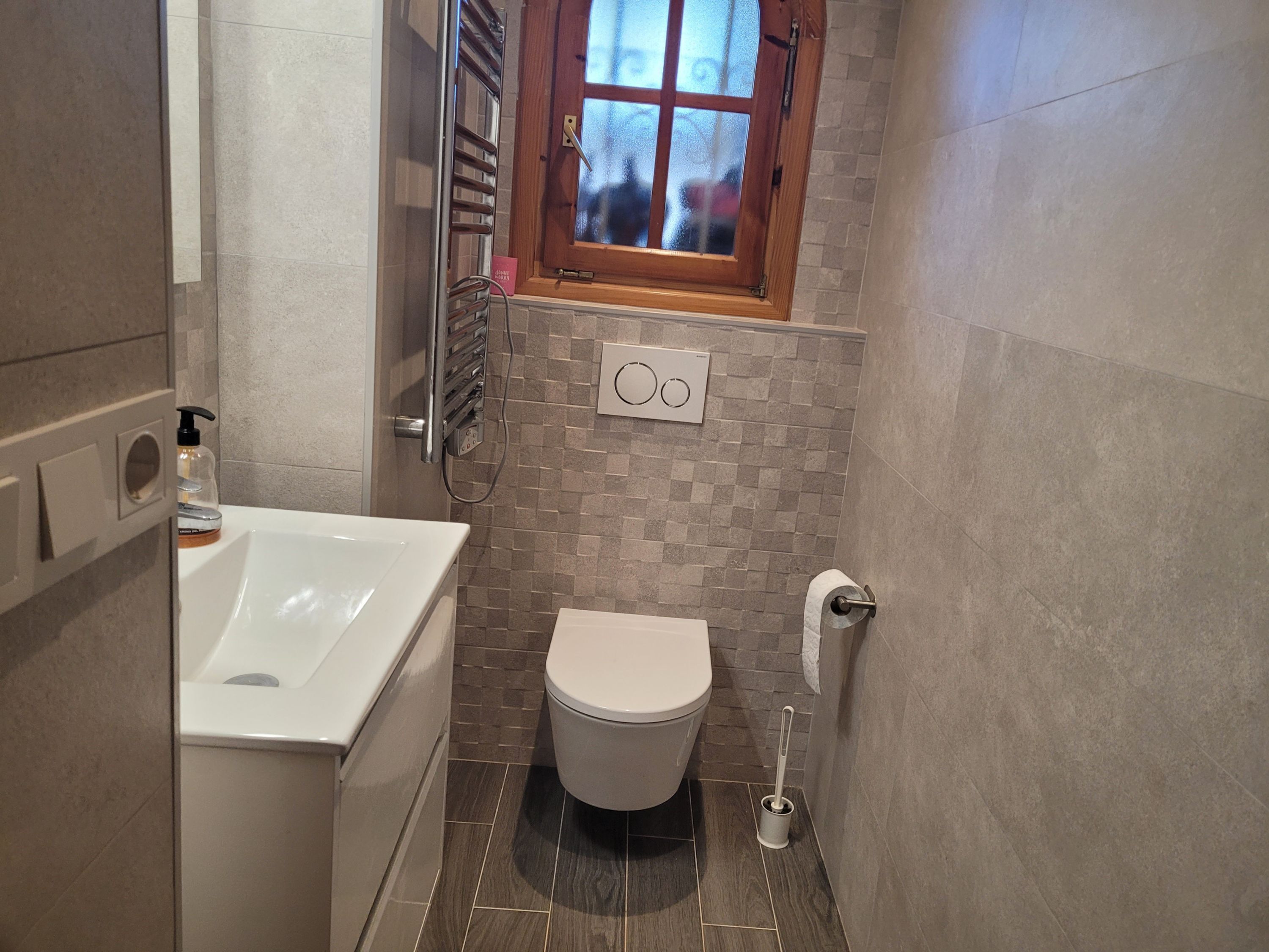Un baño con bañera, inodoro y una ventana sobre el inodoro.