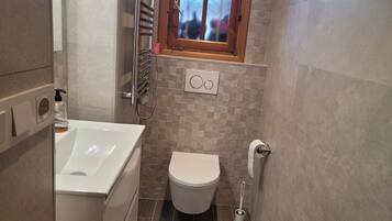 Un baño con bañera, inodoro y una ventana sobre el inodoro.