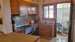 A kitchen with wooden cabinets, a countertop, a sink, and a window with a view of bicycles outside. - Dup2136 in Denia With 2 Bedrooms and 1 Bathrooms (Denia)