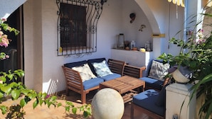 An outdoor seating area with a sofa, table, and chairs, a decorative wall, and potted plants. - Dup2136 in Denia With 2 Bedrooms and 1 Bathrooms (Denia)