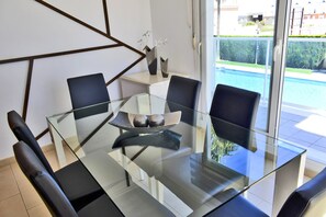 A modern dining area with a glass table, black chairs, and a view of a swimming pool. - Ap2700 in Oliva With 2 Bedrooms and 2 Bathrooms (Oliva)