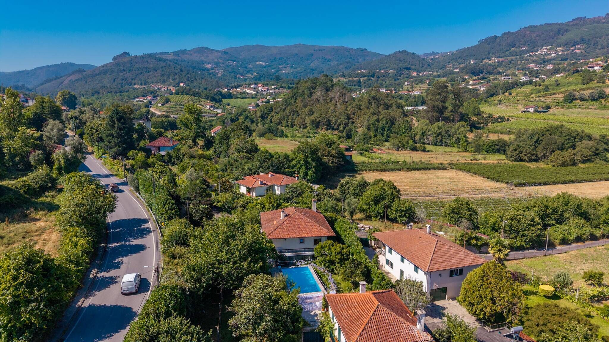 An aerial view of a residential area with houses, a road, and a swimming pool.