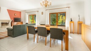 Una sala moderna con comedor, chimenea y ventanas grandes que dan a zonas verdes.