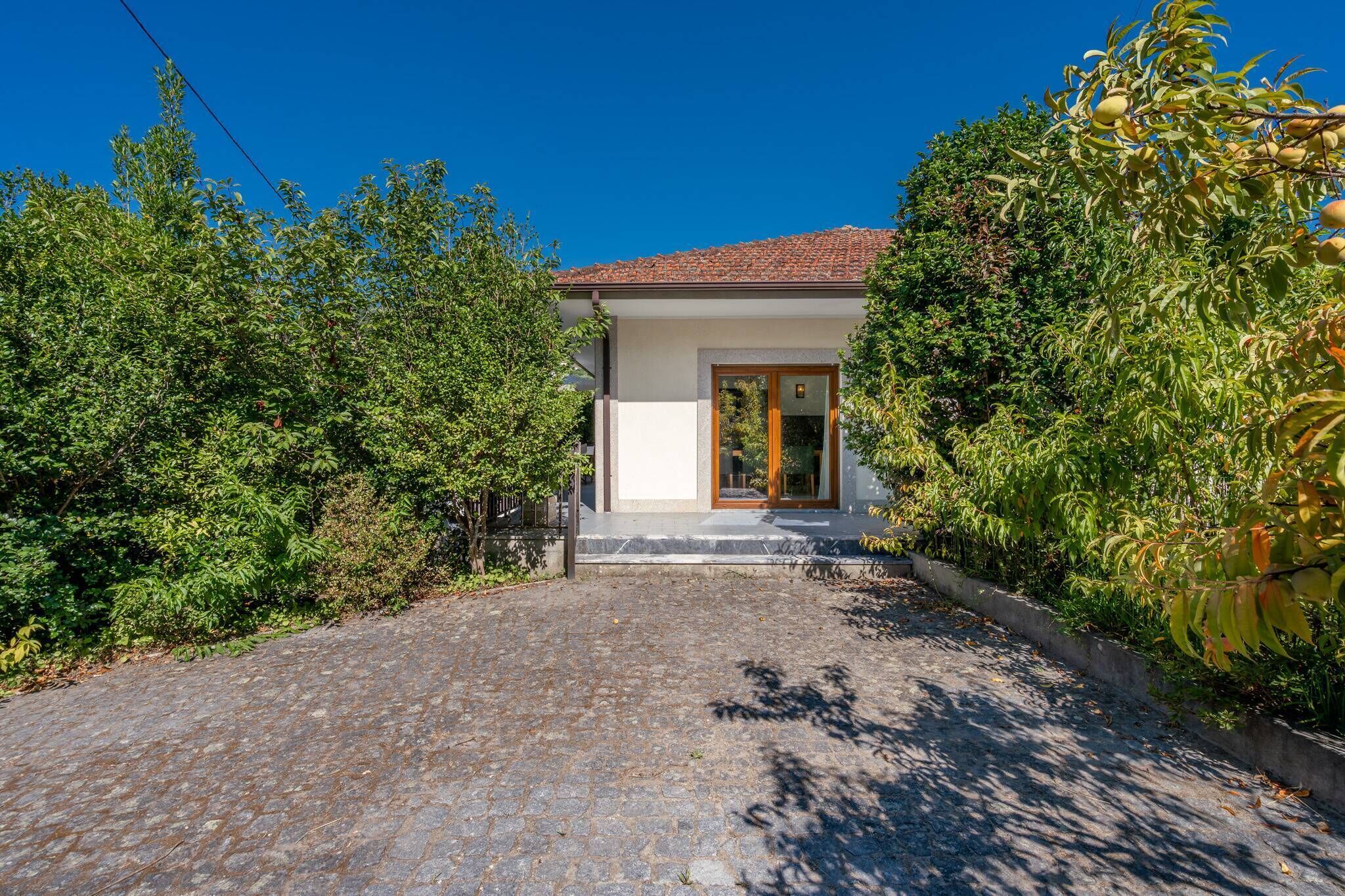 A house with a cobblestone driveway, a wooden door, and a tiled roof.
