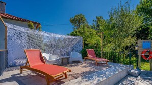 Un patio al aire libre con sillas reclinables y valla de celosía blanca.