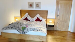Una cama de madera con ropa de cama floral, dos lámparas de noche y una puerta de madera.