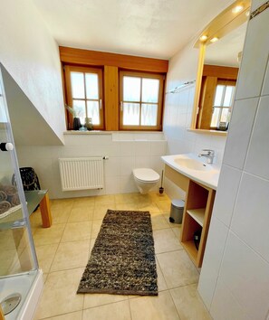 A bathroom with a toilet, sink, and window. - Vacation home Benedikt, Füssen Eschach (Füssen)