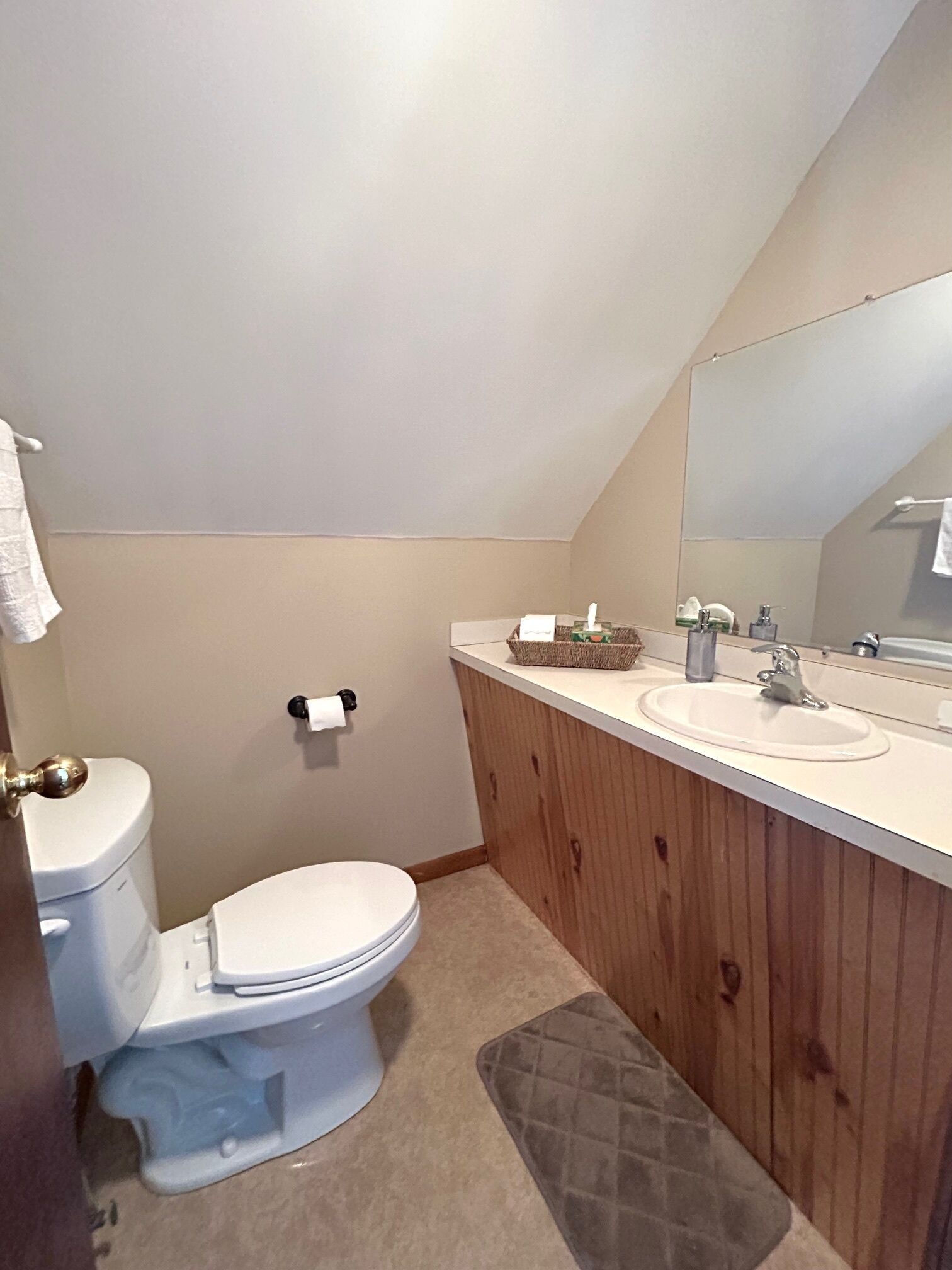Een badkamer met toilet, wastafel en spiegel.
