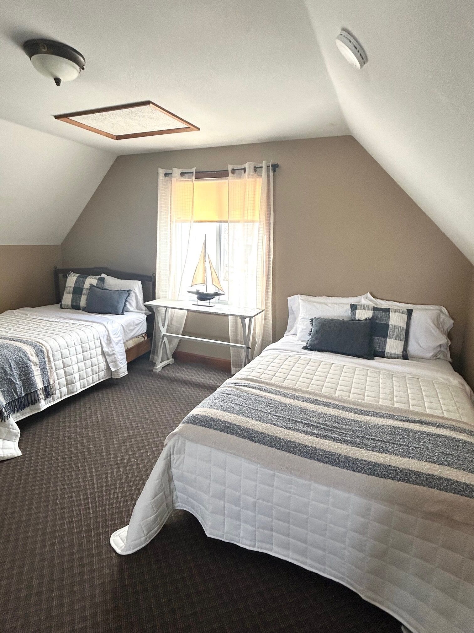 Een kamer met twee bedden, een tafeltje en een raam met gordijnen.