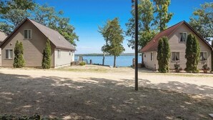Hileras de cabañas de dos pisos con camino de grava, rodeadas de árboles y vistas al lago.