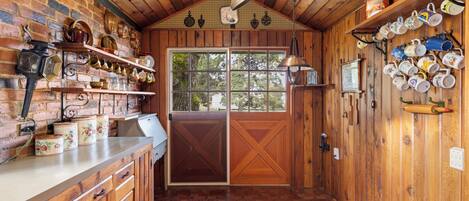 Une cuisine rustique avec des murs en bois, un mur de fond en briques et une grande fenêtre.