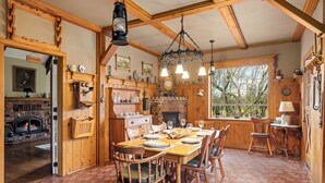 Un intérieur rustique avec des éléments en bois, une cheminée en briques, une table à manger en bois et des chaises.