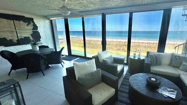 A spacious living area with a large window overlooking a beach. - Ocean 382 -First Floor Beachfront Condo2 bedrooms/2 baths (Ponte Vedra Beach)