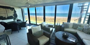Un vaste espace de vie avec une grande fenêtre donnant sur une plage.