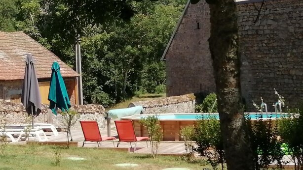 Ein Gebäude aus Stein mit Pool, Außenbereich zum Sitzen und einem Baum im Vordergrund.