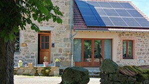 Ein Steinhaus mit Solardach, Holztür und Mauerwerk.