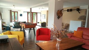 Ein Wohnzimmer mit einem Holztisch, einem roten Sessel, einem gelben Sofa und einem Tischtennisch.