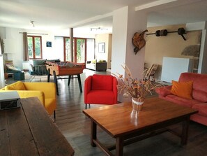 A living room with a wooden coffee table, a red armchair, a yellow sofa, and a ping pong table. - La Picolina - CHARENSAT (CHARENSAT)