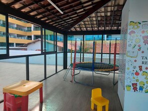 Un'ampia area giochi al coperto con un trampolino, un tavolino e una sedia.