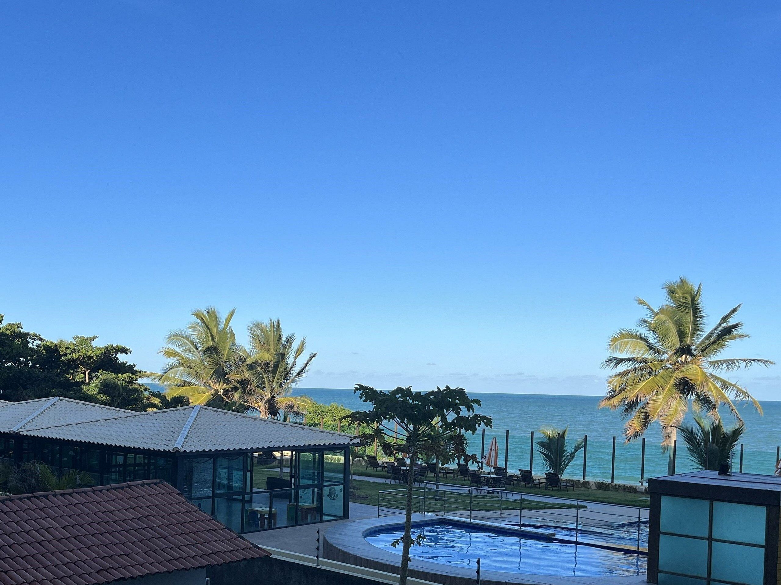 Un resort con piscina, palmeras y vista al océano.