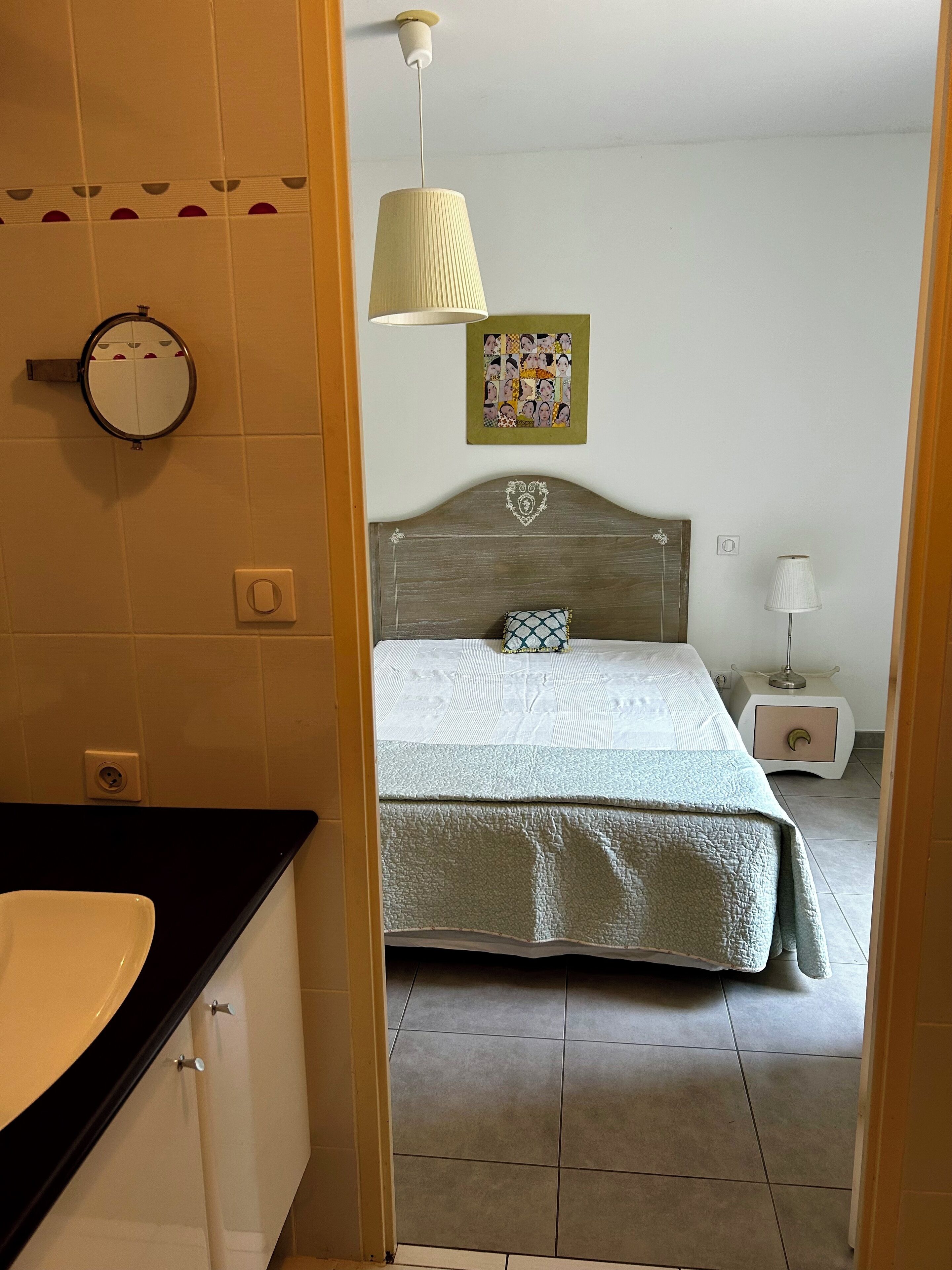 Une chambre à coucher comprenant un lit, une table de chevet, une lampe et un miroir fixé au mur.
