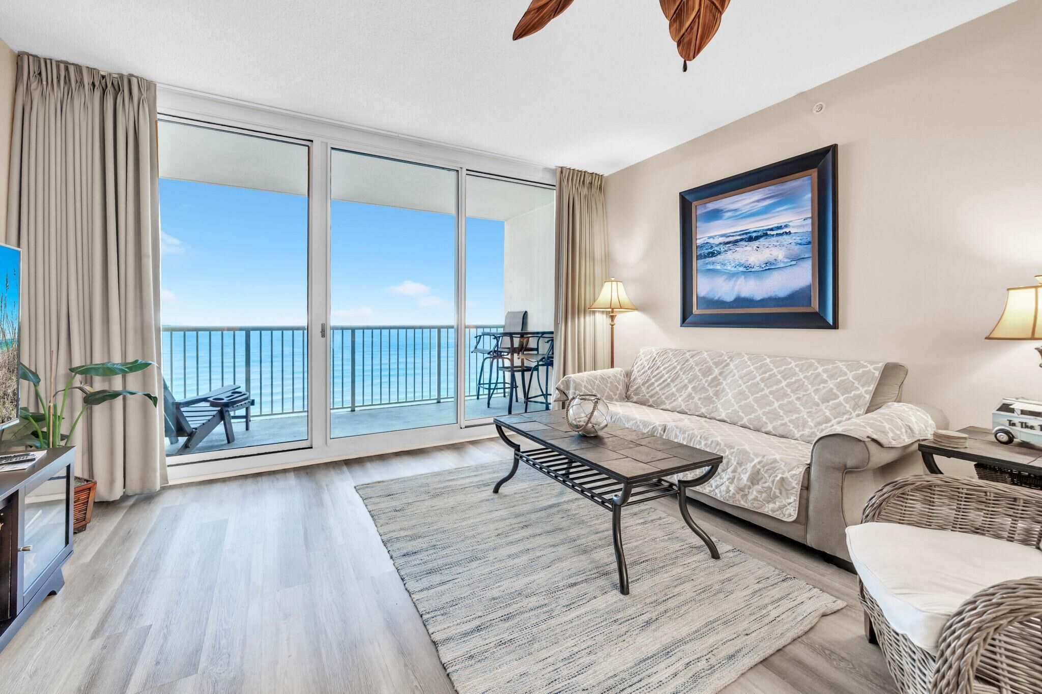 A spacious living room with a large sliding glass door leading to a balcony with a view of the sea.