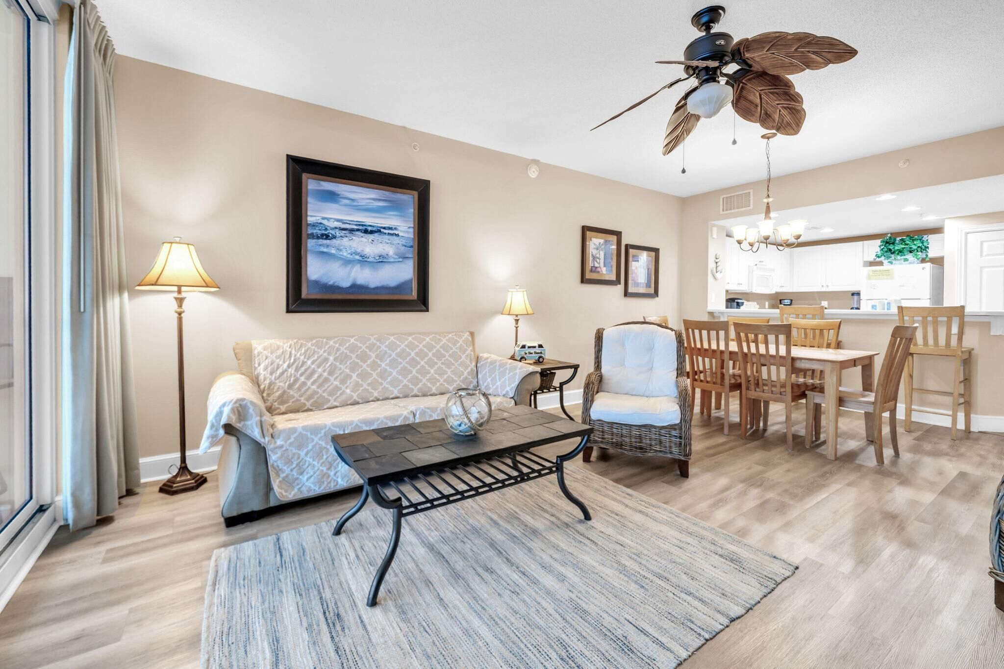 A living room with a sofa, coffee table, and a dining area with chairs and a table.