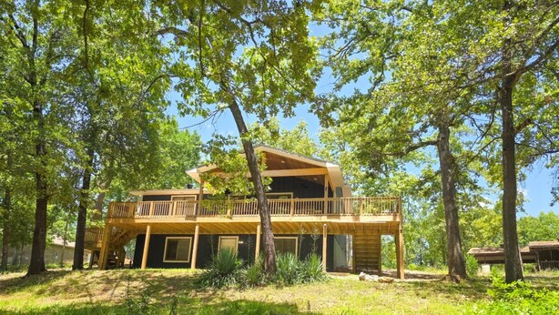 A two-story wooden cabin with a balcony, surrounded by trees. - 4BR/2BA with Huge Deck, Bonus Room, Swimming/Fishing & Stunning Seasonal Views! (Mountain Home)