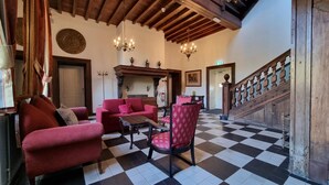A spacious lobby with a checkered floor, red upholstered furniture, and a wooden staircase.