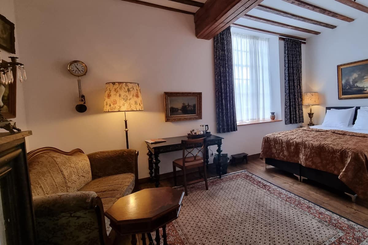 Une chambre confortable avec un lit, un bureau, une chaise, un tapis et un tableau accroché au mur.