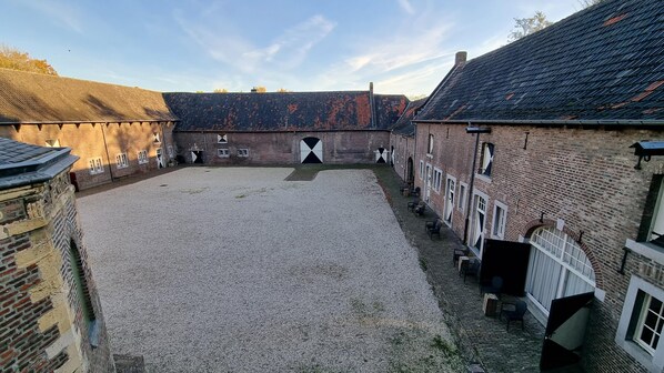 A courtyard with a gravel ground, brick buildings, and a large white door at the center. - Kasteelhotel Terborgh, BW Signature Collection (Schinnen)