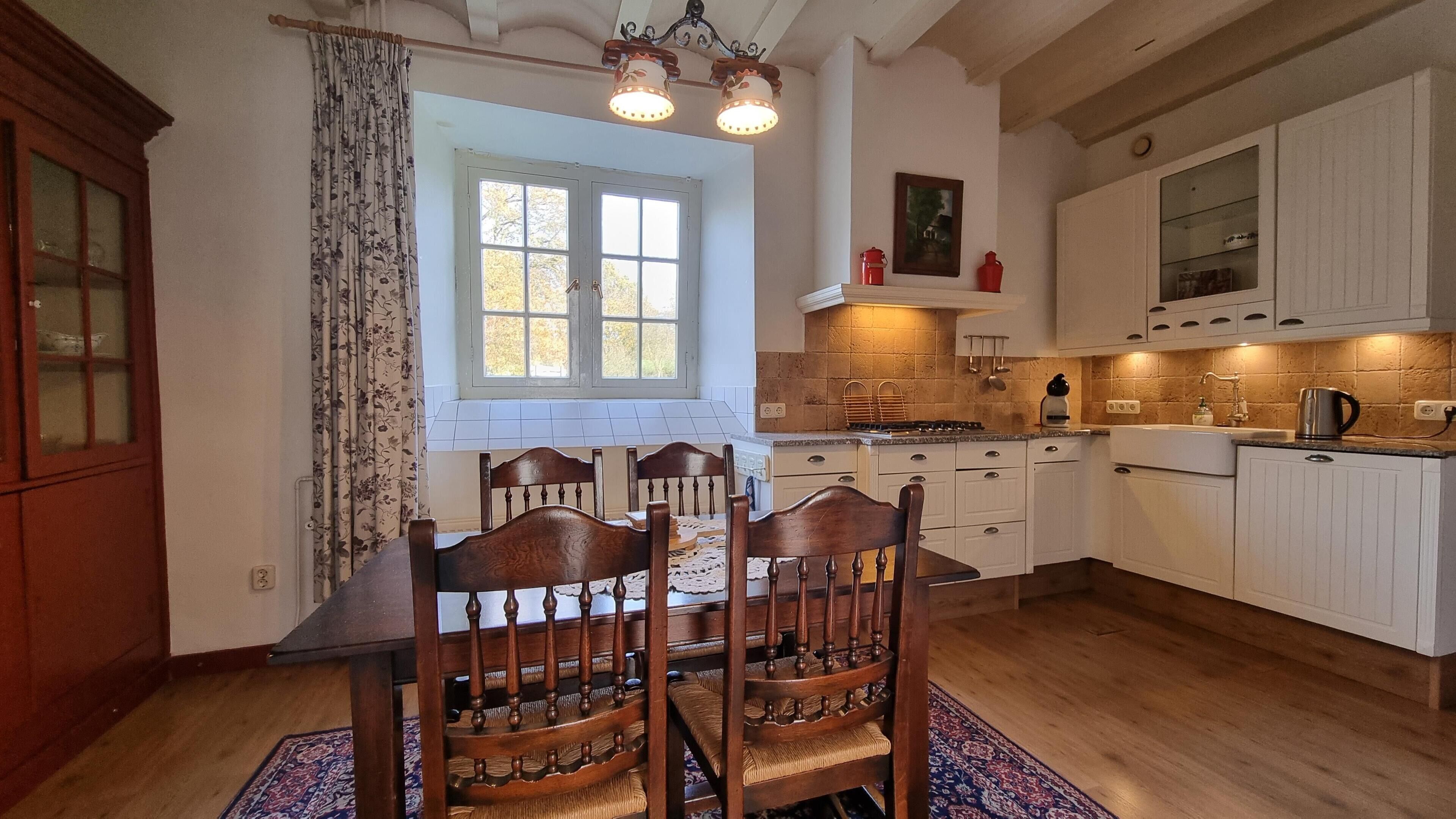 A kitchen with a wooden dining table, chairs, and a window.