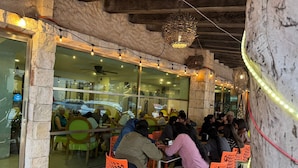 An outdoor dining area with stone walls and orange chairs. - All Inclusive MDH (Cancun)
