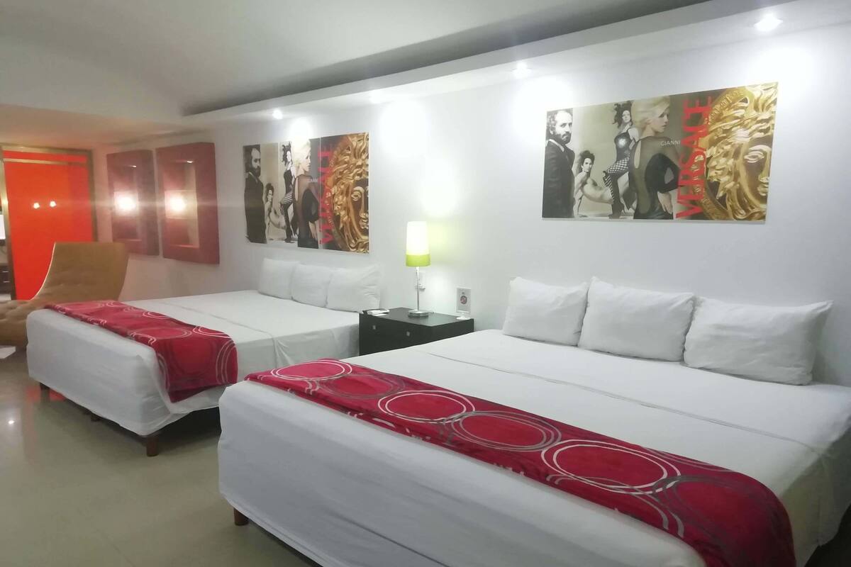 A hotel room with two beds, a nightstand, a chair, and artwork on the walls.